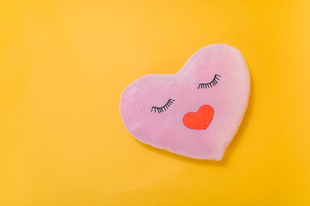 pink heart shaped pillow on yellow surface